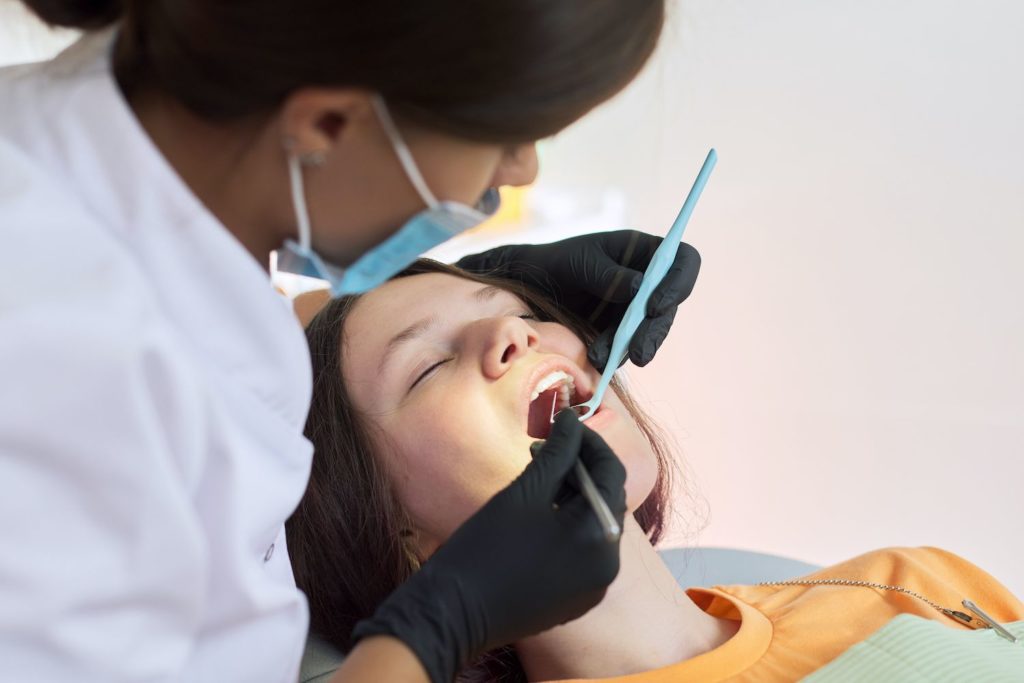 Dental professional using a scaler and mirror to clean patient's teeth dental cleanings dentist in Columbia Maryland