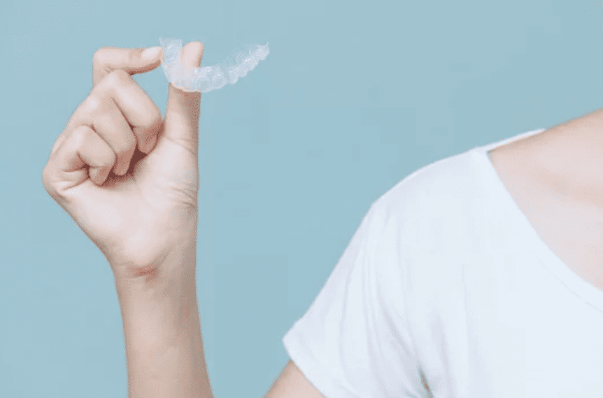 cropped image of person in white shirt holding an invisalign tray cosmetic dentistry dentist in Columbia Maryland