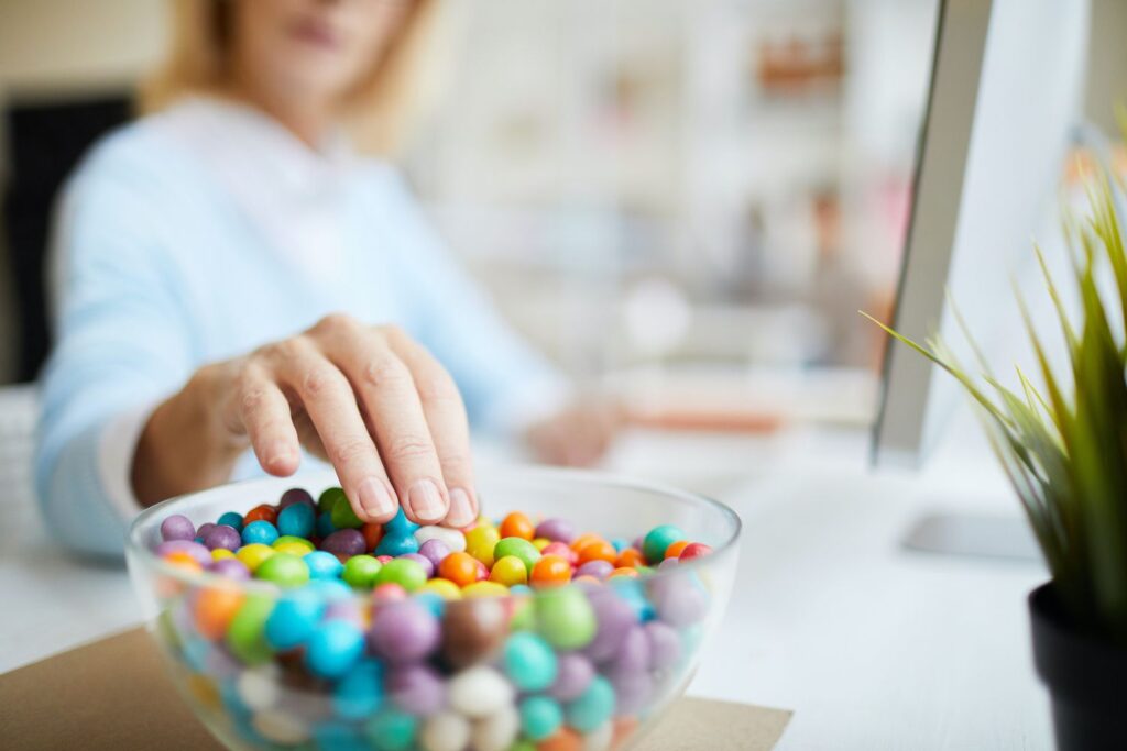 focused image of woman eating candy out of a clear bowl while working sugar effects preventative dentistry dentist in Columbia Maryland